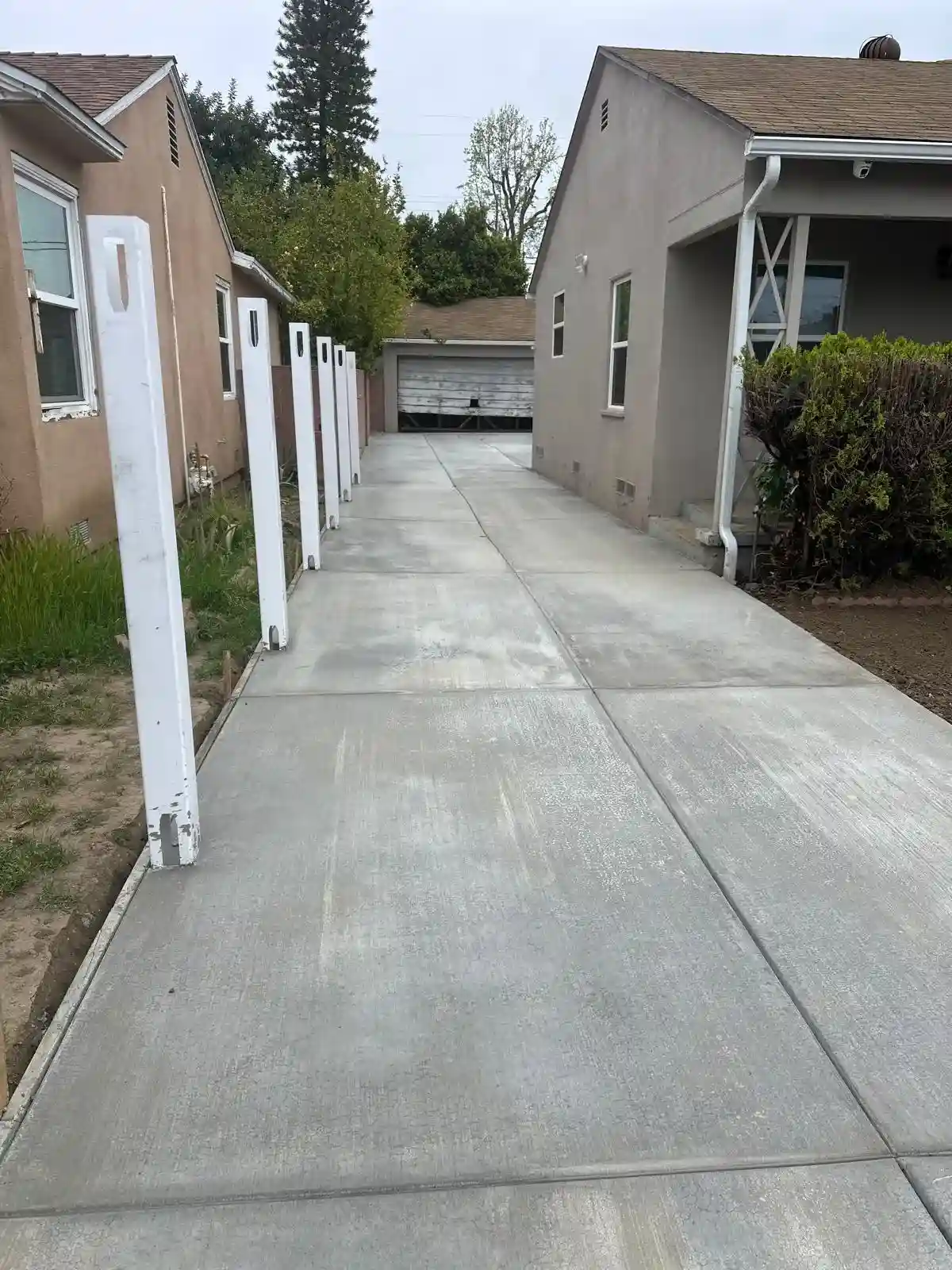 New Concrete Driveway Installation at Pasadena Residence 2 Long concrete driveway extending past houses, leading to garage.